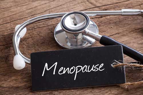 Stethoskop auf Holz mit Menopause Wort als medizinisches Konzept