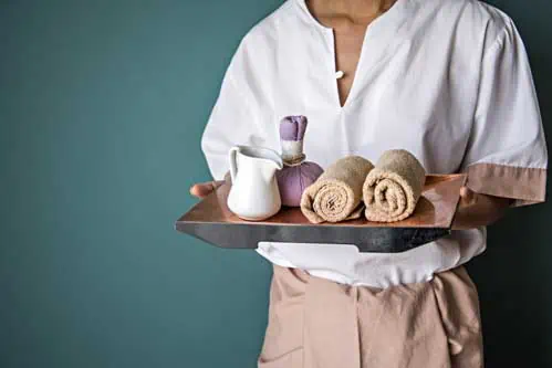 Wellness und Spamanagement - Frau mit gerollten Handtüchern und Massageöl
