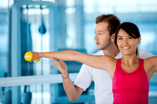 Sport- und Fitnesstraining | Schöne Frau im Fitnessraum mit ihrem Trainer