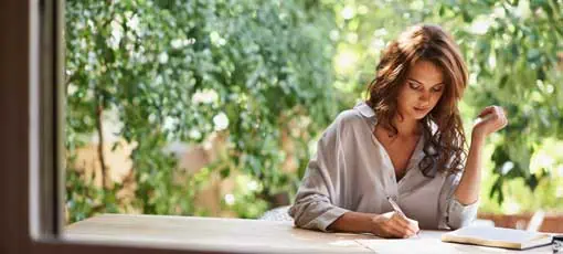 Autor/in werden - Schreiben lernen | Sie wird ein berühmter Schriftsteller werden. Aufnahme einer attraktiven jungen Frau, die in einer entspannten Umgebung im Freien schreibt.