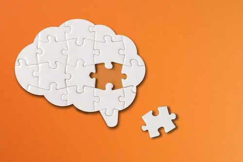 Professioneller Umgang mit Demenz im Alter | Brainförmige weiße Puzzle mit Kopienraum auf orangefarbenem Hintergrund, fehlendes Teil des Gehirnpuzzles, psychische Gesundheit und Probleme mit dem Gedächtnis