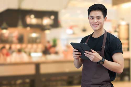 Food & Beverage-Manager | Nahaufnahme asianischer Mann-Barista-Holtablette zur Prüfung der Bestellung beim Kunden auf unscharfem Hintergrund des Café-Cafés , KMU-Geschäftskonzept