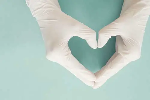 Grundlagen der Patientensicherheit | Ärzte Hände mit medizinischen Handschuhen, die Herzform machen