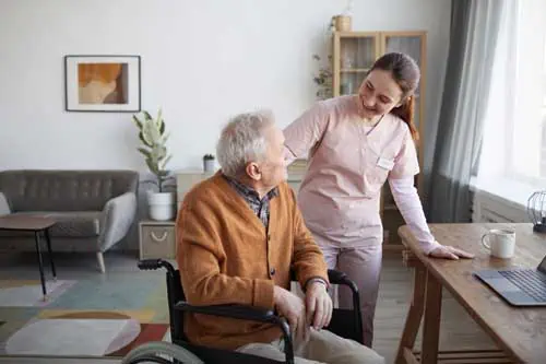 Fachkraft in der häuslichen Pflege | Porträt einer lächelnden Krankenschwester, die Senioren im Rollstuhl im Ruhestand hilft